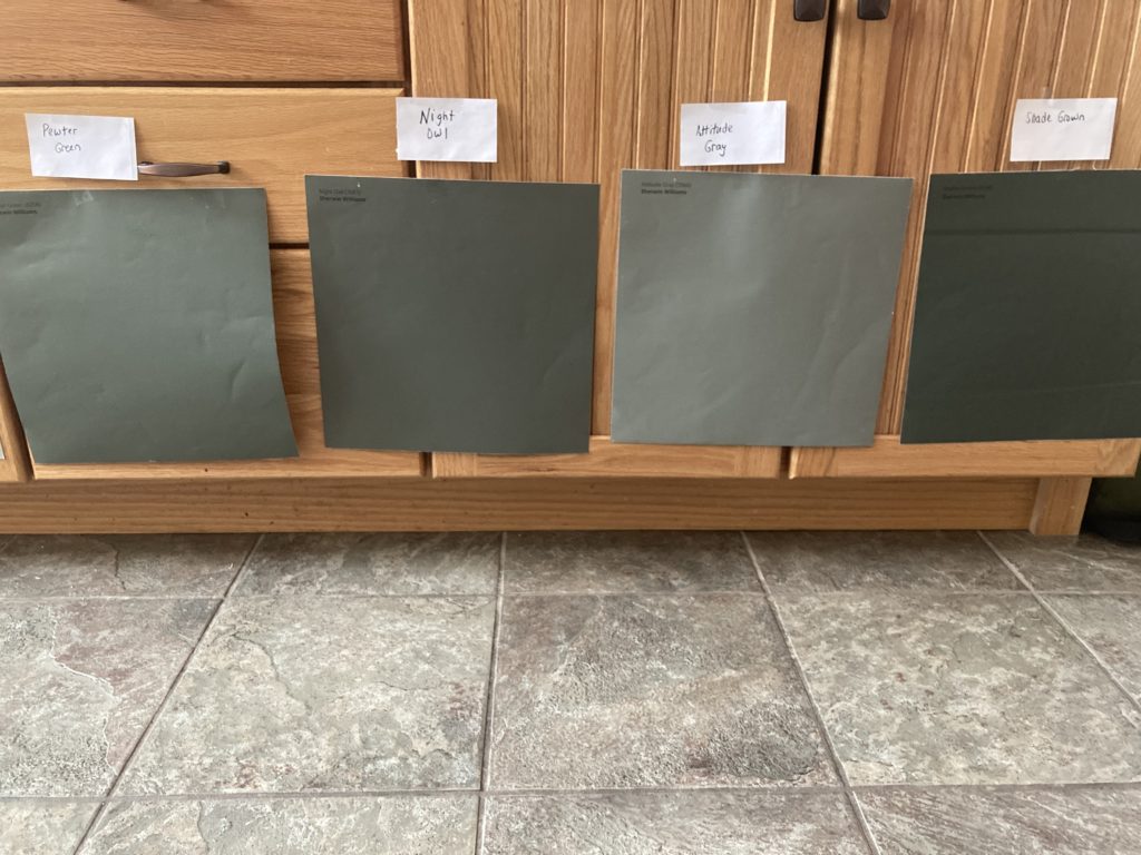 dark green paint samples on an oak kitchen island with beige taupe tile floor. Samplize peel and stick with Kylie M Interiors