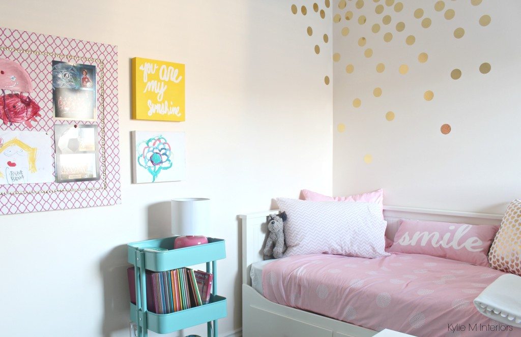 ikea raskog cart in a girls bedroom with pink walls and homemade corkboard with fabric, gold circle or dot vinyl decals and ikea bed