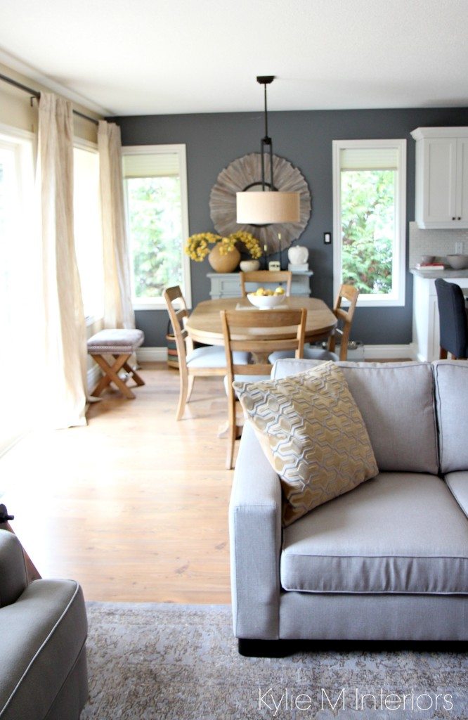 Modern country or farmhouse style open concept dining room and living room with gray and warm gold and yellow accents. Couch, rug and paint color all coordinate