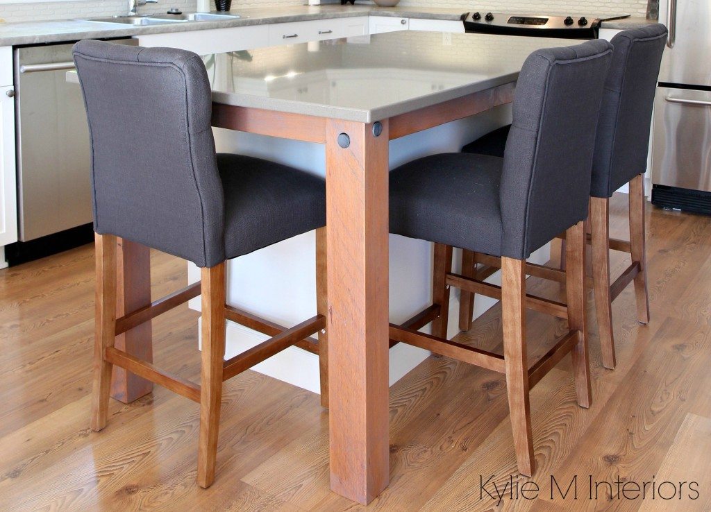 Rustic reclaimed legs to support a gray quartz island countertop with gray stools