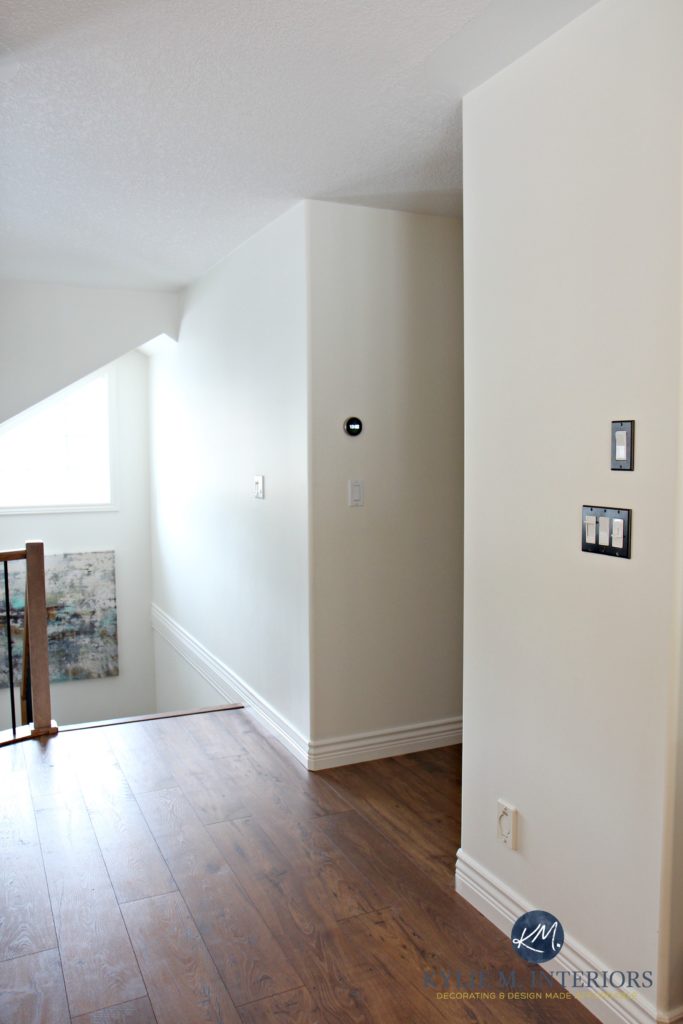 Sherwin Williams Creamy in a north facing stairwell and a dark hallway with laminate wood flooring. Kylie M Interiors