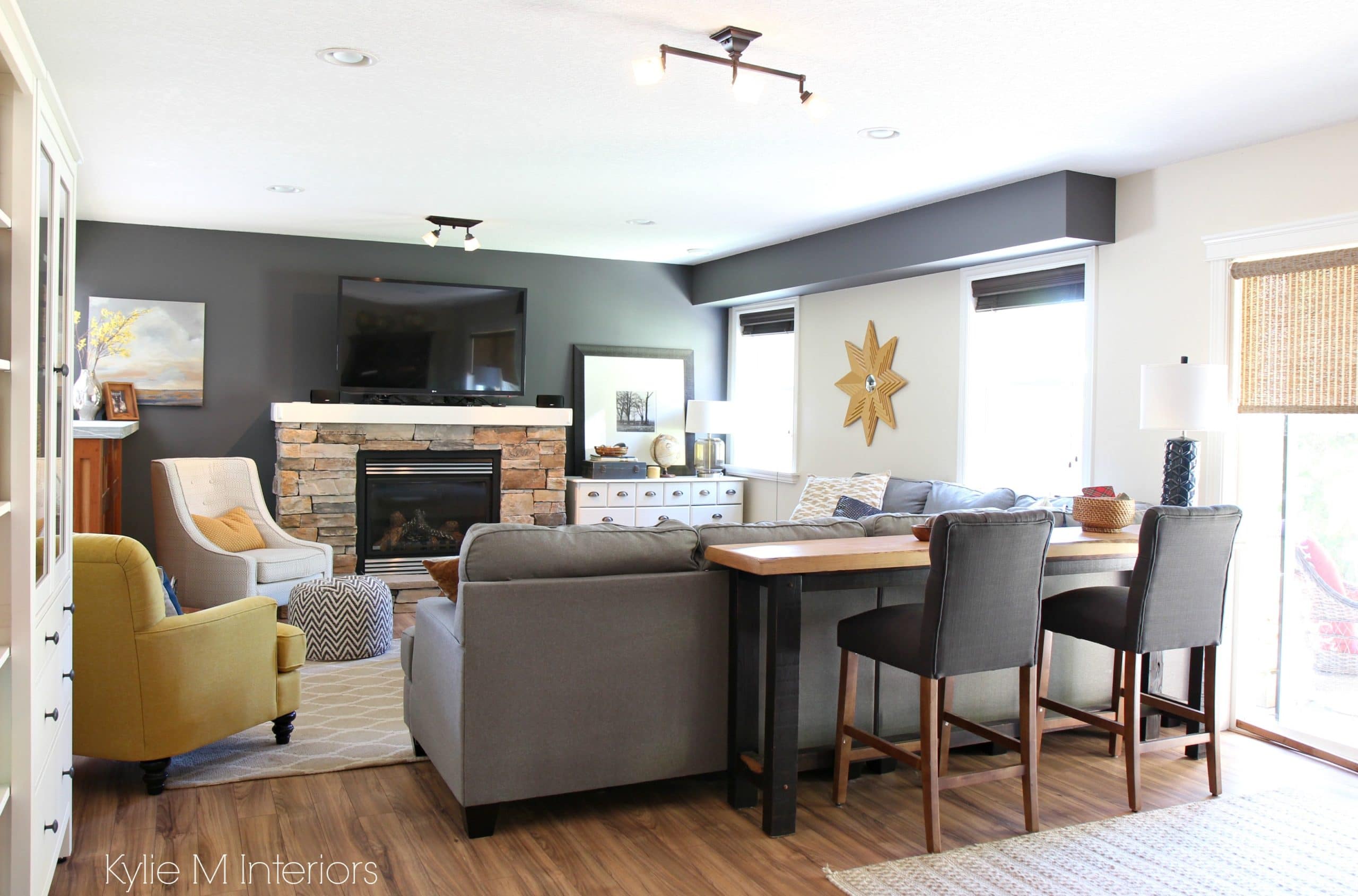 Family room decorating ideas with tv over stone fireplace, gold accents, Benjamin Moore Gray, sectional, live edge sofa table and stools by Kylie M Interiors e-design
