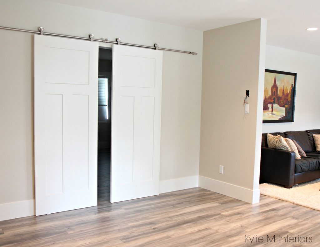 benjamin-moore-edgecomb-gray-leading-into-master-bedroom-with-2-white-sliding-barn-doors-and-laminate-wood-flooring