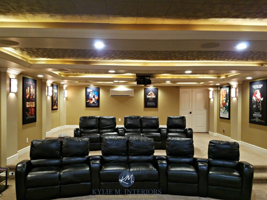 Home theatre room remodel with black recliners, Benjamin Moore Lenox Tan, Tyler taupe and Davenport Tan ceiling tiles with movie posters. Kylie M Interiors E-design and color consultation