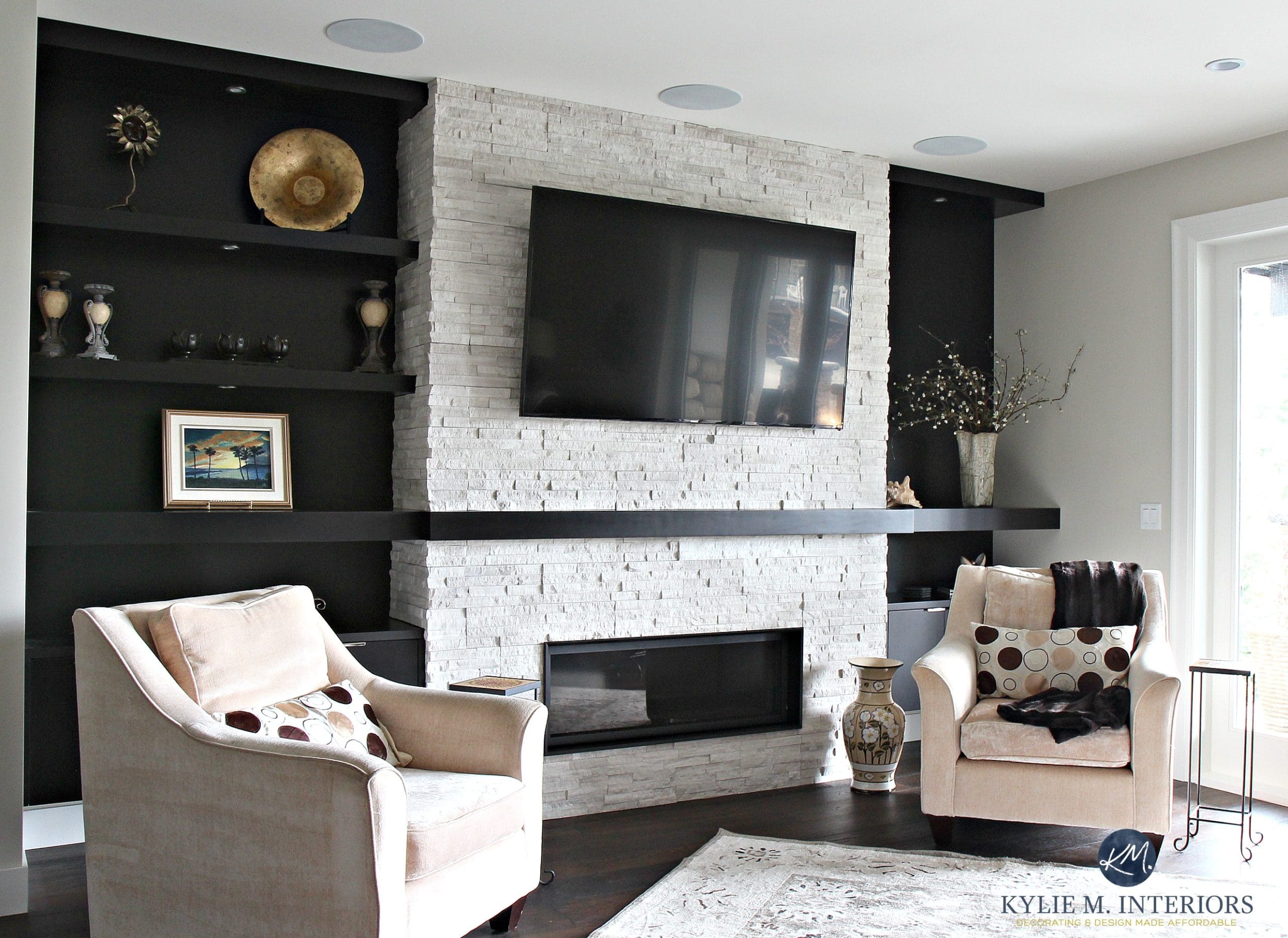 E-decor and Online Decorating Services. Beautiful ledgestone, travertine fireplace with Tv above, dark wood mantel and built-in bookshelves wtih 2 cream accent chairs. Kylie M Interiors