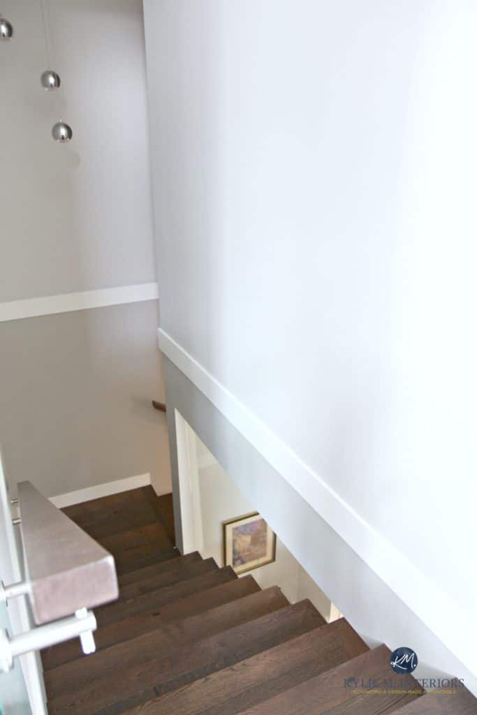 Stairway that is opened up to see into the wine room that is under the stairs. Wood stairs and gray walls. Kylie M Interiors Decorating and Design, E-decor services