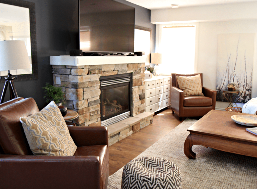 family room with tv on mantel above stone fireplace with 2 leather accent chairs and Sherwin Williams Cyberspace. Kylie M Interiors E-design and color consulting expert