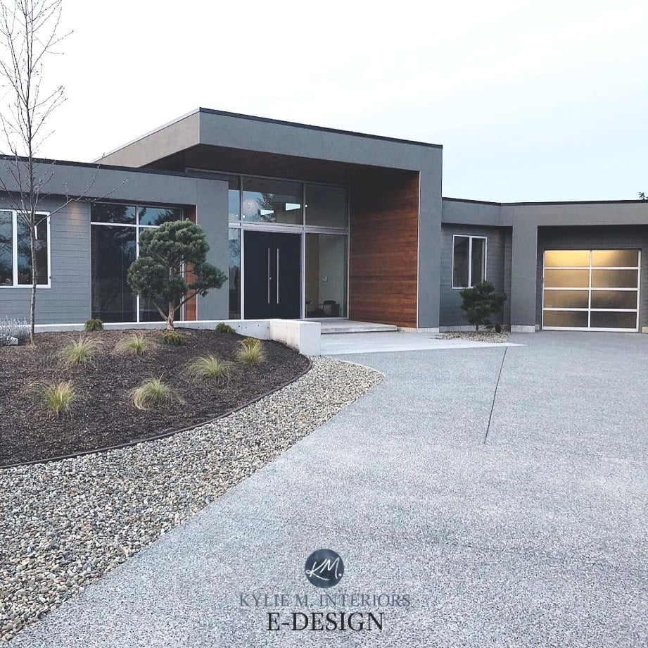 Exterior stucco of modern or comtemporary home painted Benjamin Moore Amherst Gray, dark gray witih black front door, frosted glass garage doors, and aluminum silver windows, wood accent 