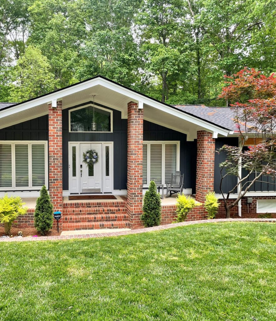 Exterior of mid-century modern style home with red orange brick, James Hardie Iron Gray, Sherwin Extra White trim and front door.