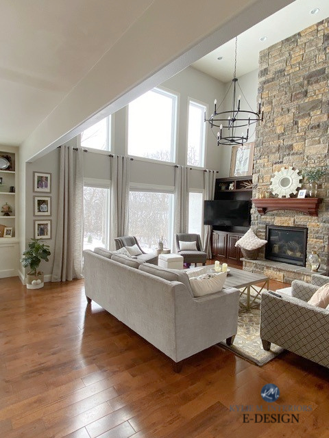 Large tall stone fireplace, Sherwin Williams Agreeable Gray on walls in family room or living room, vaulted ceiling. Kylie M. Oak wood floor, best greige paint colour