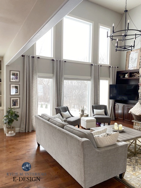 Living room, tall windows and ceilings, Sherwin Williams Agreeable Gray, best greige paint colour on walls, oak floor, taupe neutral sofa. Kylie M.