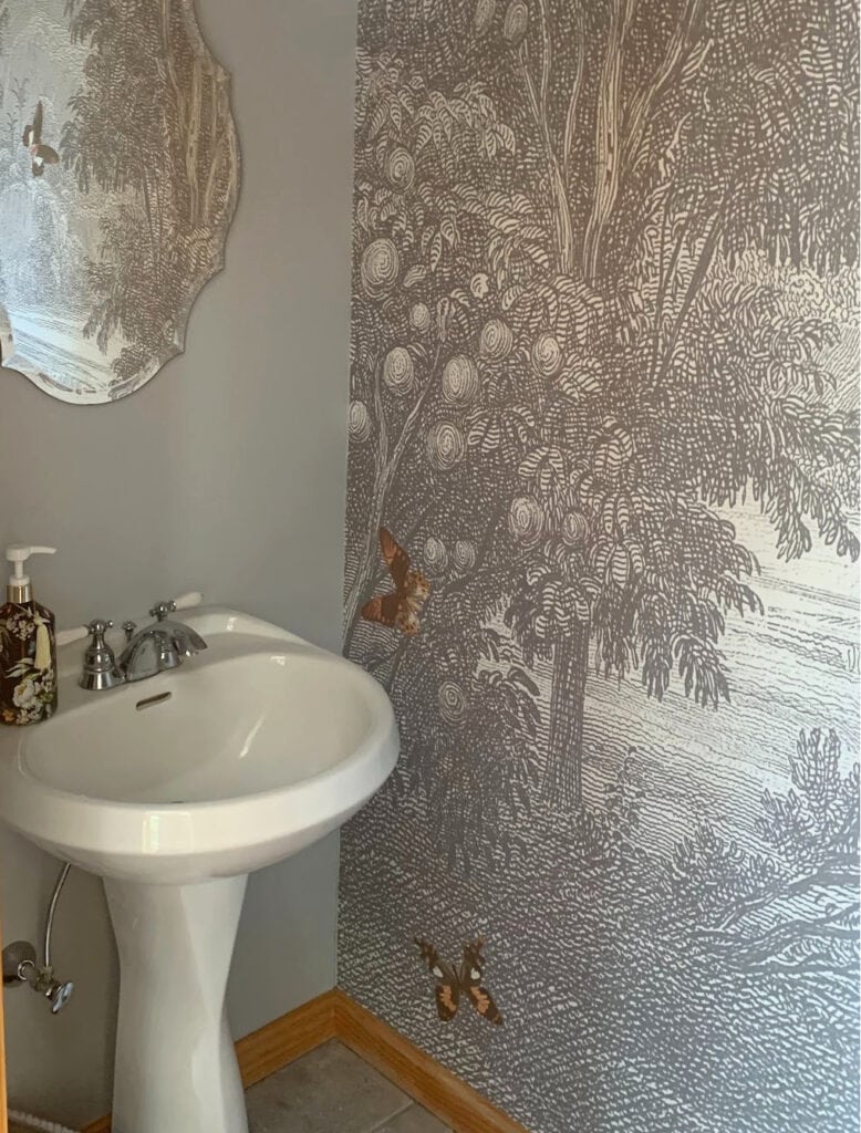 Foliage, forest scene wallpaper in small powder room or bathroom with vinyl floor and gray walls. Pedestal sink and no window