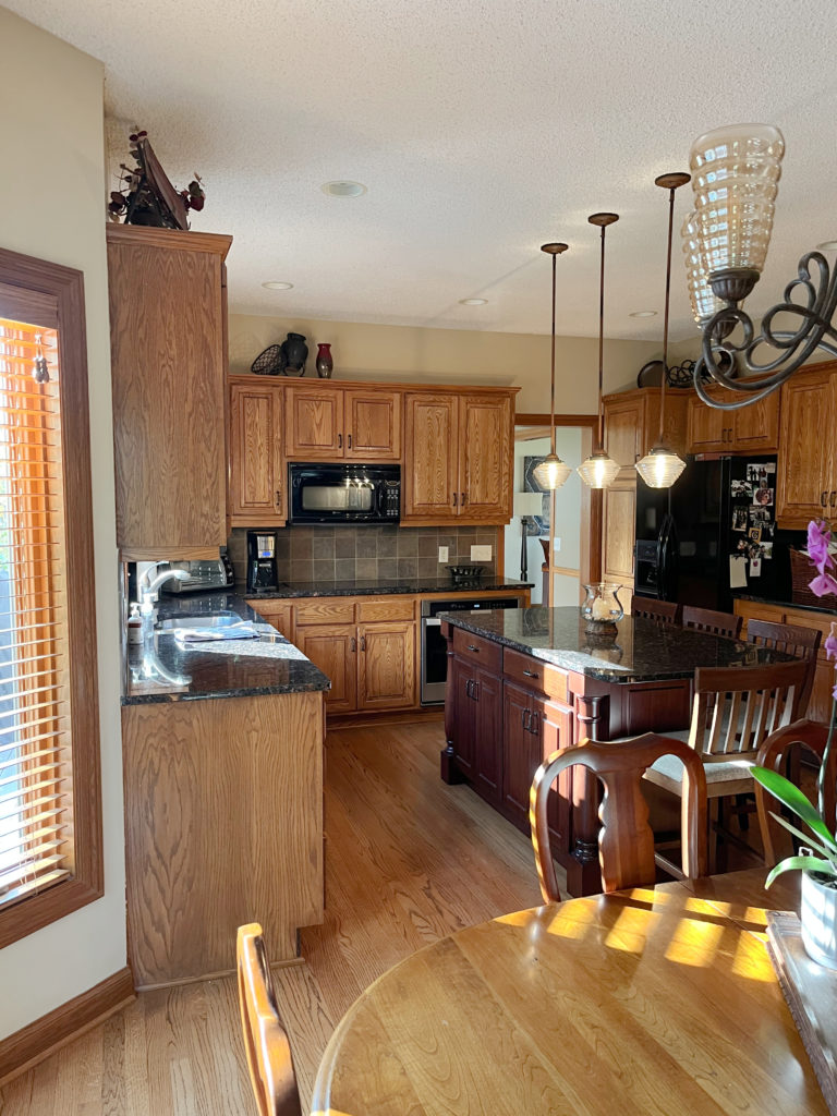 Oak cabinets, wood floor, oak wood trim, orange hue, black granite countertop, beige walls.