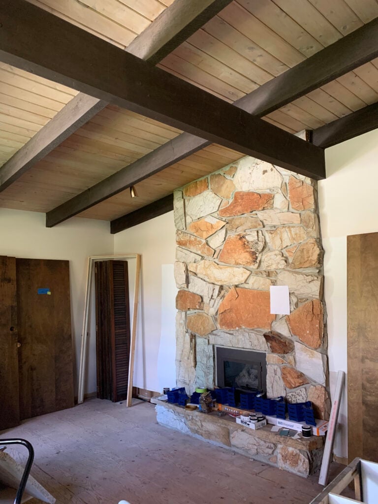 1960 orange stone fireplace, wood tongue and groove ceiling with dark wood beams