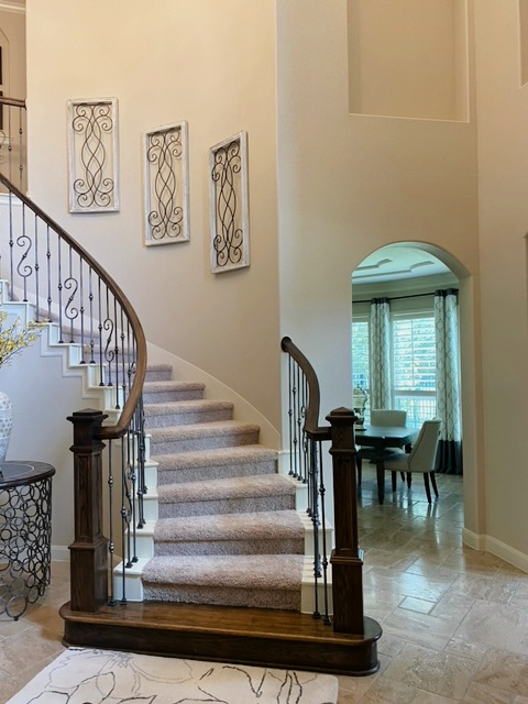 Sherwin Williams Kilim Beige wall paint colour in curved staircase with taupe carpet, travertine tile floor BEFORE EDESIGN with Kylie M Interiors