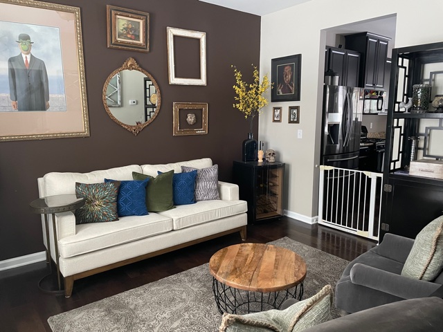Sherwin Williams Mega Greige with dark brown feature accent wall, off white sofa, dark wood floor, blue green accents and gallery wall. CLIENT PHOTO