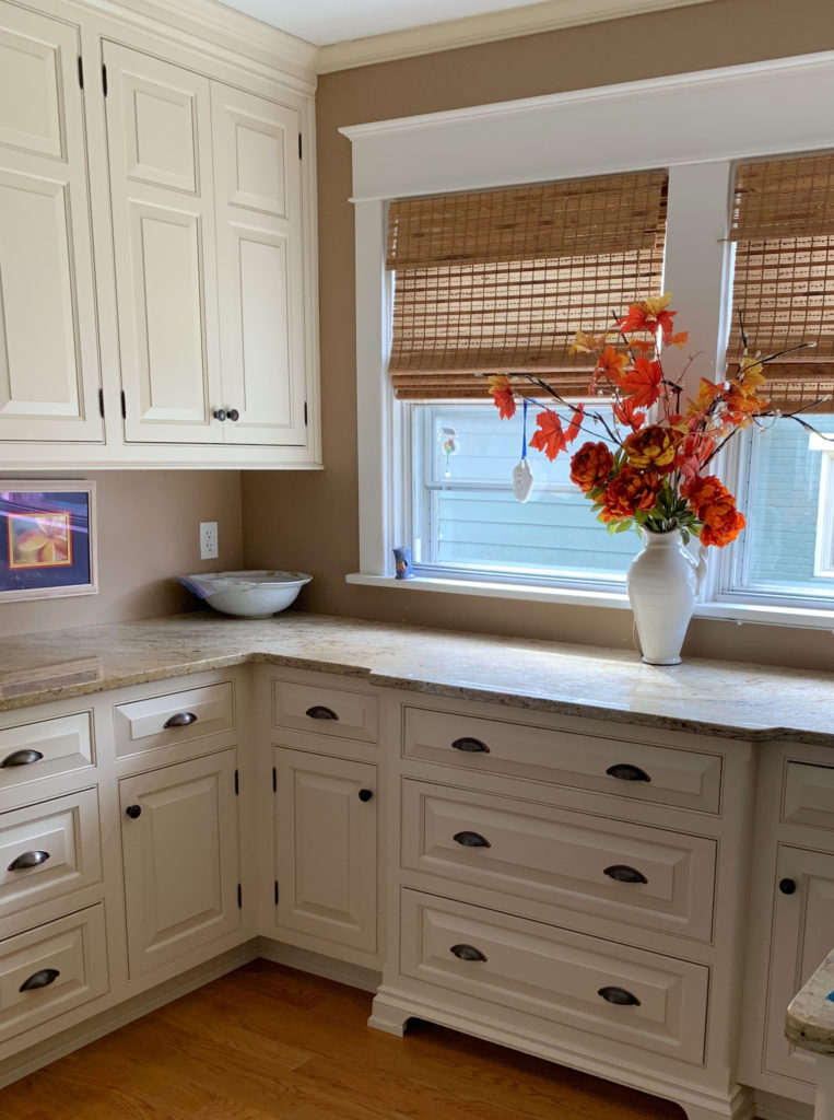 Cream painted cabinets, similar to Sherwin Williams Antique White, Benjamin Moore Navajo White, granite countertops, darkre beige paint colour on the walls.