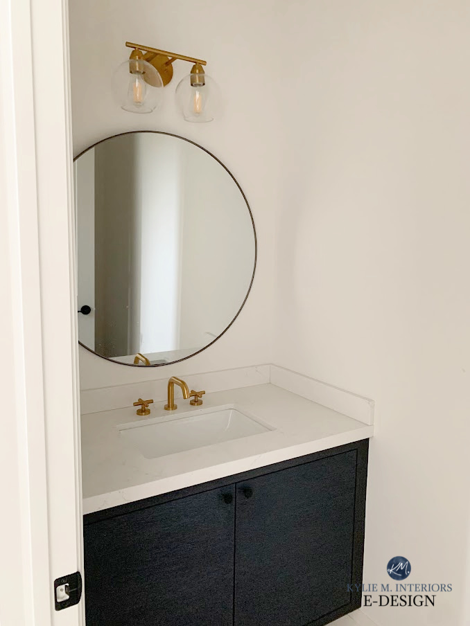 Benjamin Moore White Dove on walls in small powder room, black vanity, white countertop, round mirror gold light and faucet. Kylie M Interiors Edesign