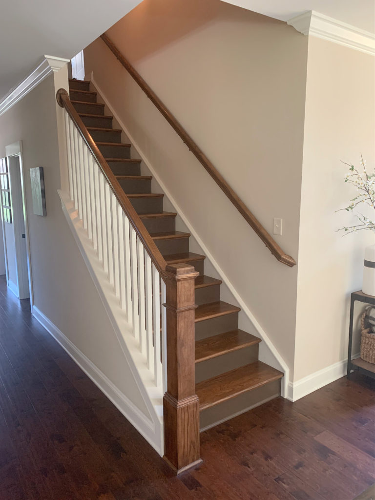 Sherwin Williams Kilim Beige, best warm neutral paint colour on stair wall with red oak cherry toned wood flooring.