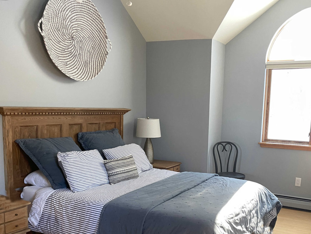 Bedroom with wood headboard and floor, Benjamin Moore Coventry Gray, wood trim. Kylie M Interiors Edesign client photo