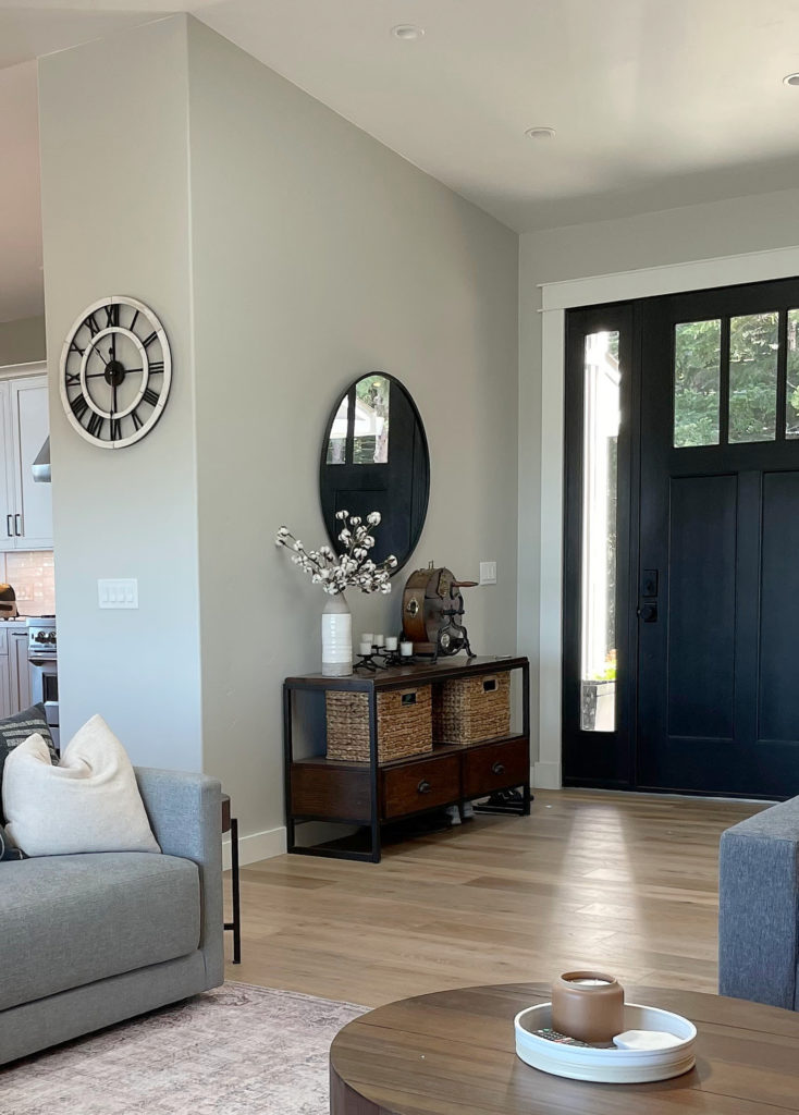 Entryway of foyer with light wood flooring, black front door, home decor and Sherwin Williams Repose Gray. Kylie M.