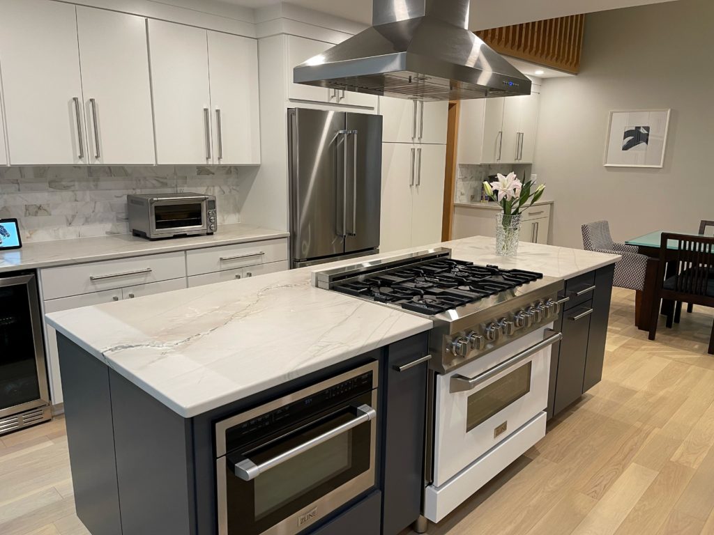 Sherwin Williams Pure White painted flat panel cabinets, stove top in island painted in Cyberspace, walls are gray in Big Chill, marble look white quartz countertop