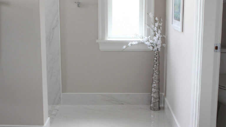 Benjamin Moore Balboa Mist in a bathroom with marble look tile floor and tile baseboards, white trim