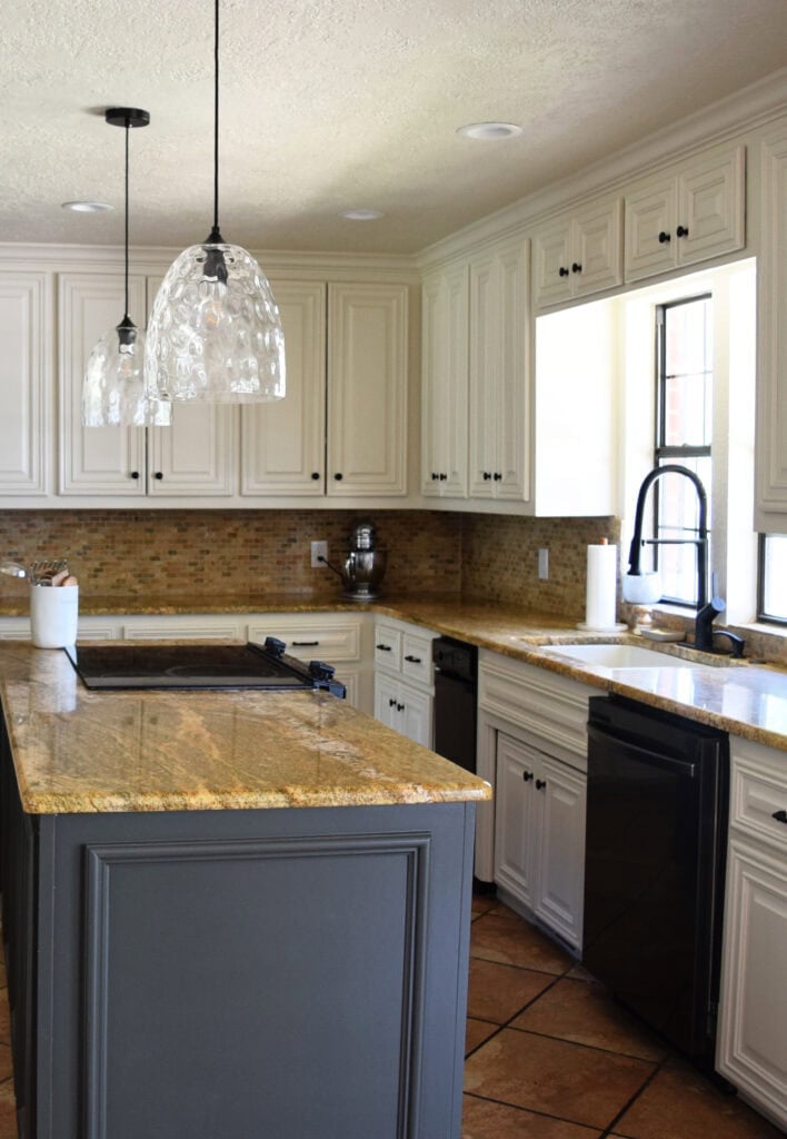 Black appliances, Benjamin Moore Ashwood Moss gray green painted island, painted cabinets, Moderate White, Sherwin. Travertine, granite countertops, orange tile floor. Kylie