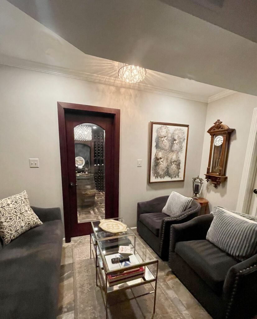 Sherwin Williams Worldy Gray in dark family room basement, lounge leading into wine room with cherry wood door, slate tile floor. Kylie M.