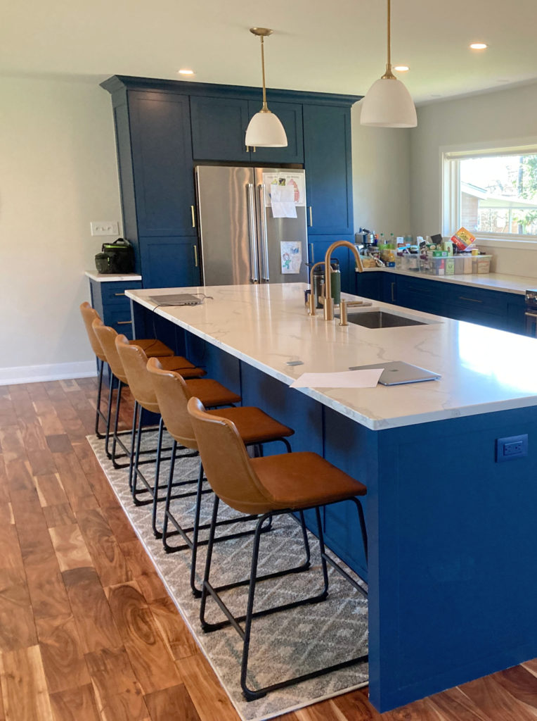 Benjamin Moore Gentlemans Gray dark blue paint colour on kitchen cabinets, lower cabinets, island, stainless steel, white quartz countertop, red wood floor
