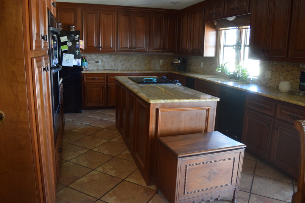 BEFORE kitchen with wood cherry or maple cabinets before painting. tile floor, granite countertops, travertine