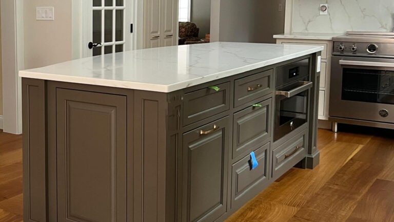 Sherwin Williams Porpoise on painted kitchen island with white quartz countertop, oranged toned wood flooring