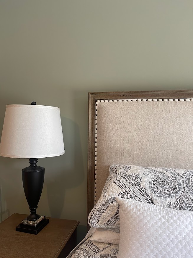 Benjamin Moore October Mist in guest bedroom with upholstered neutral fabric headboard and linens. Best green for bedrooms