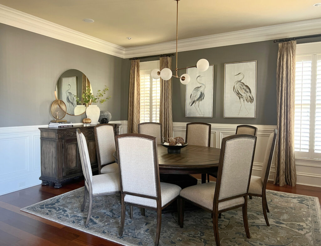 Dining room with wainscoting in Sherwin Williams Creamy, walls Benjamin Moore Chelsea Gray, ceiling Oakwood Manor. Round dark wood dining table and home decor