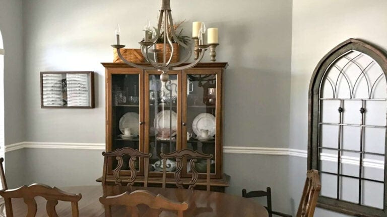 Traditional dining room with 1970s wood furniture and chair rail. Walls painted a warm gray with green