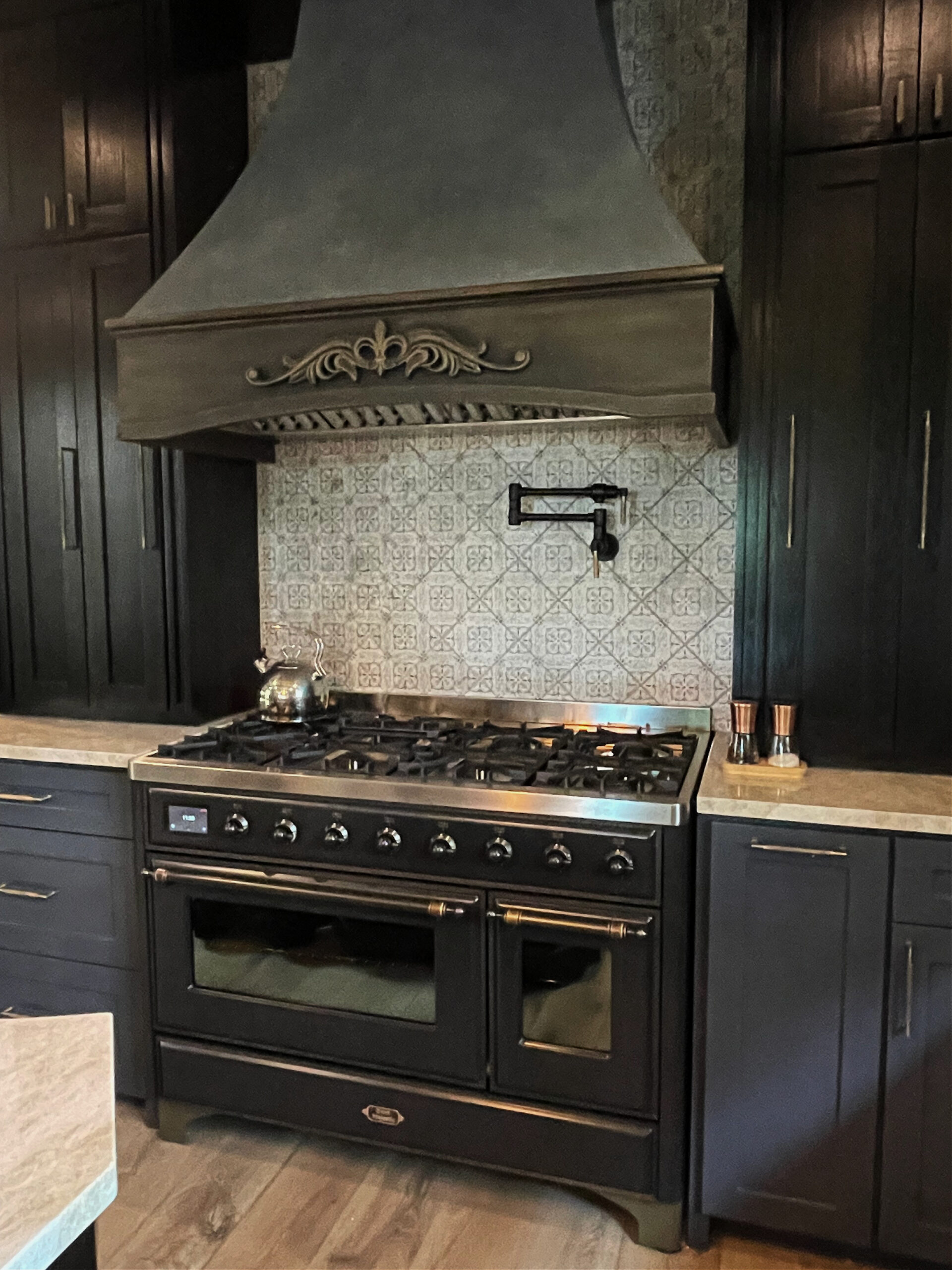 Best blue black paint color on kitchen cabinets, lowers, Benjamin Moore Mysterious, uppers dark stained wood, glazed range hood, gas stove, white oak. Kylie M ONline paint color consulting