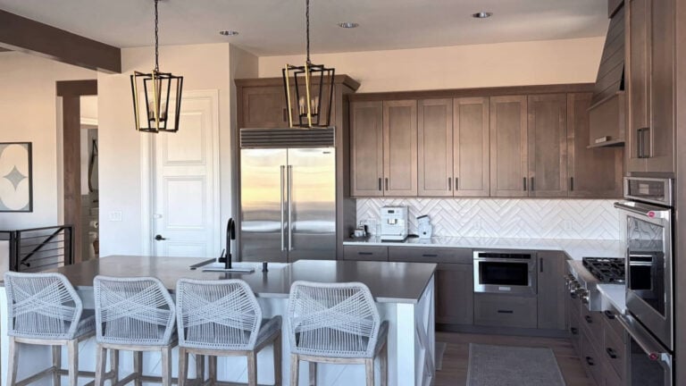 Kitchen with stained wood cabinets (maple). Drift of Mist paint color on walls with white subway tile backsplash and gray quartz.