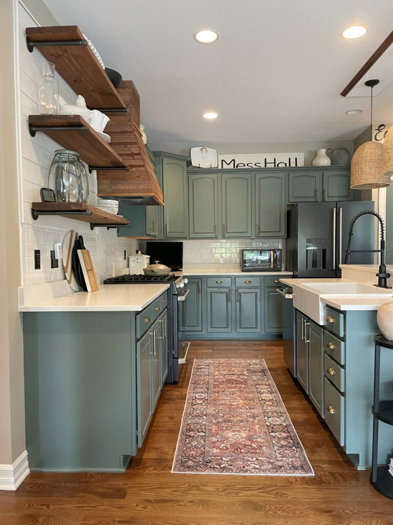Benjamin Moore Caldwell Green, modern green on painted wood kitchen cabinets, cathedral, arched door style, white quartz countertop, subway tile backsplash, floating shelves, oak floor