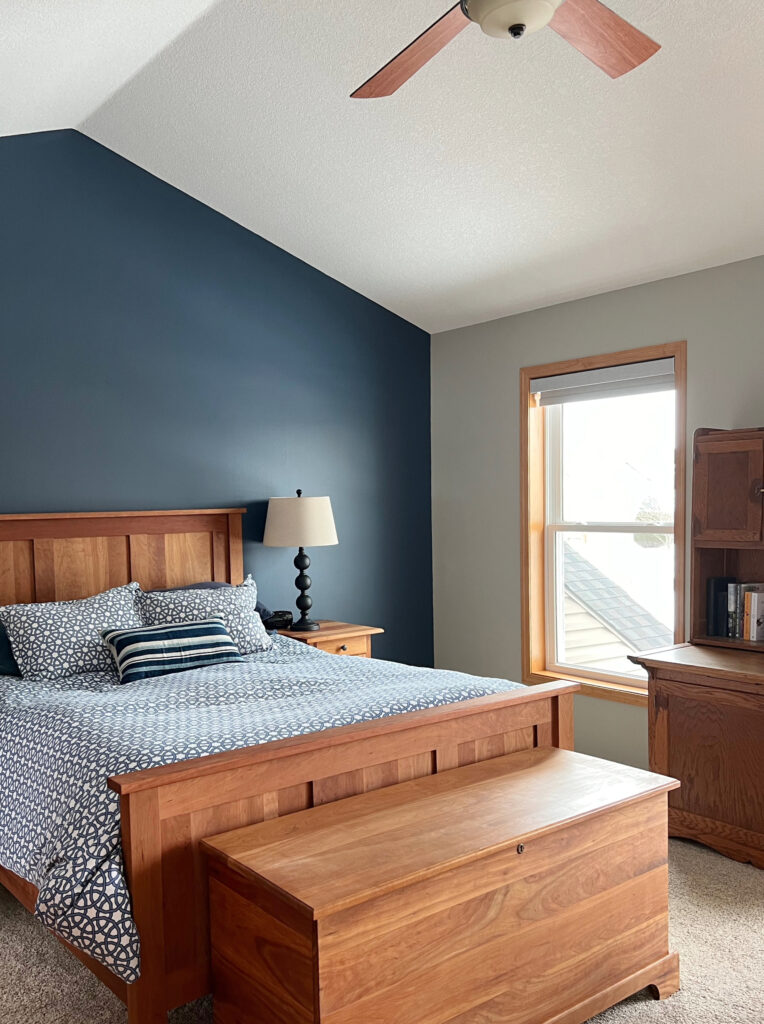 Benjamin Moore Newburyport Blue accent feature wall in bedroom behind headboard, orange stain wood trim and furniture, beige carpet, Jogging Path greige walls, KYlie M Interiors