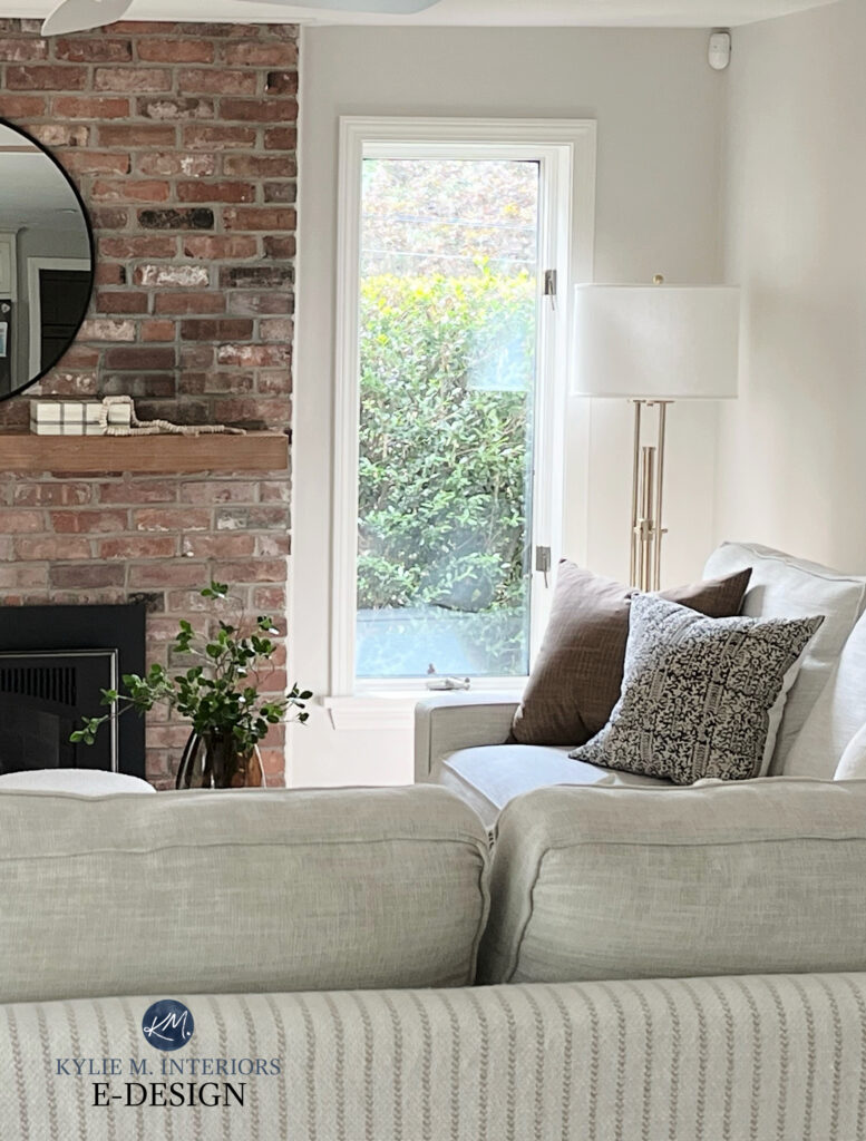 Brick fireplace in orange, red, and pink brick. wood mantel, home decor, taupe sofa, greige warm gray walls, Sherwin Williams Egret White by Kylie M ONline Paint Color expert