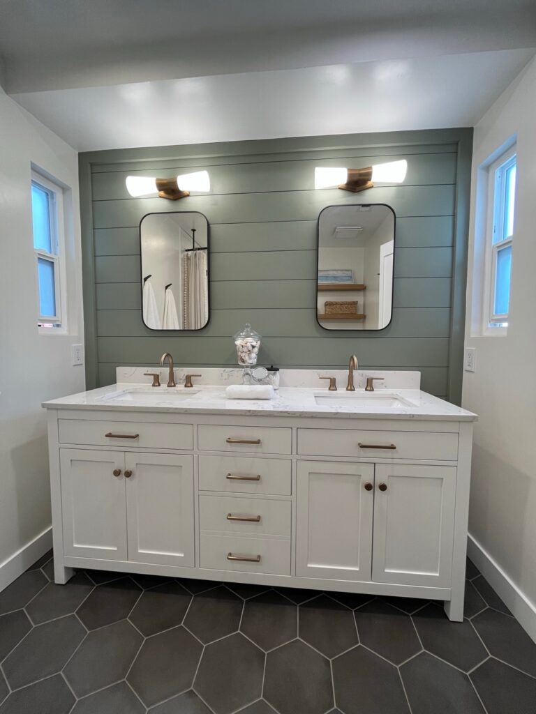 Sherwin Williams Alabaster with Evergreen Fog green accent wall in shiplap, gold brass hardware, black gray hexagon tile floor, white vanity, marble look quartz