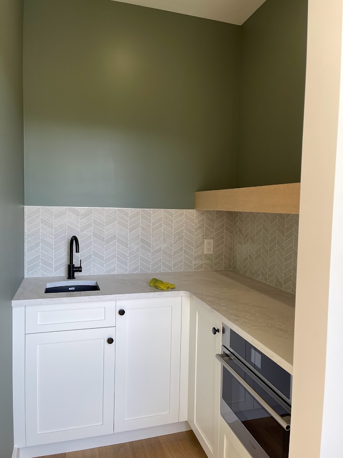 Best green paint color, Sherwin Williams Dried Thyme in small walk in pantry with White Dove cabinets, floating shelf, Omnia Quartz Monterey