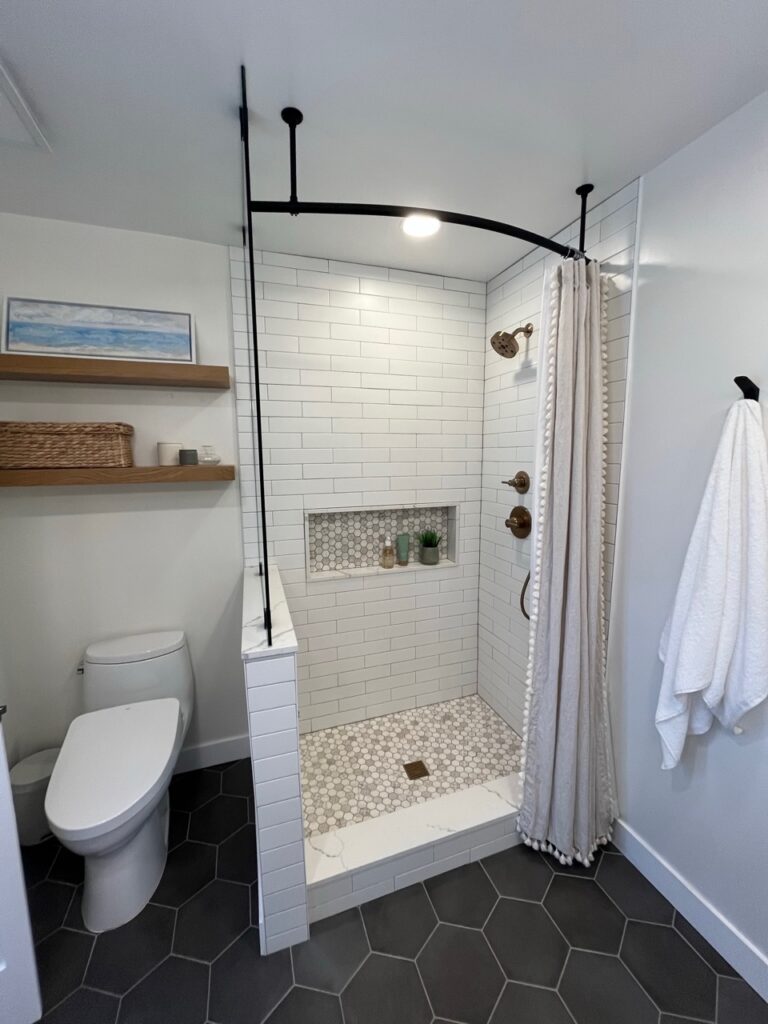 Small walk in shower with shower curtain, penny tile floor and niche alcove, dark black charcoal gary hexagon floor tile, Sherwin Williams Alabaster walls