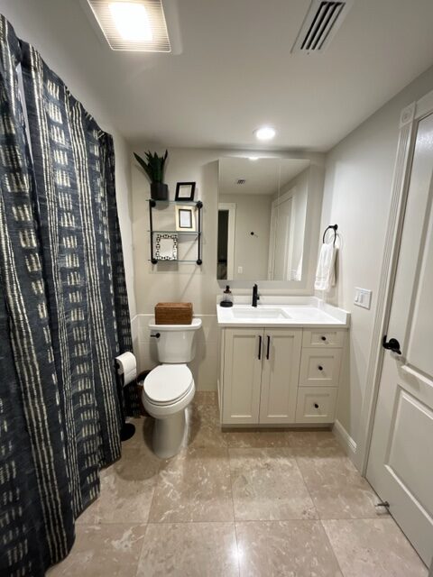 Benjamin Moore Classic Gray in bathroom with travertine tile floor, white vanity, white toilet, navy blue shower curtain. Kylie M Online Paint Color expert, consultant