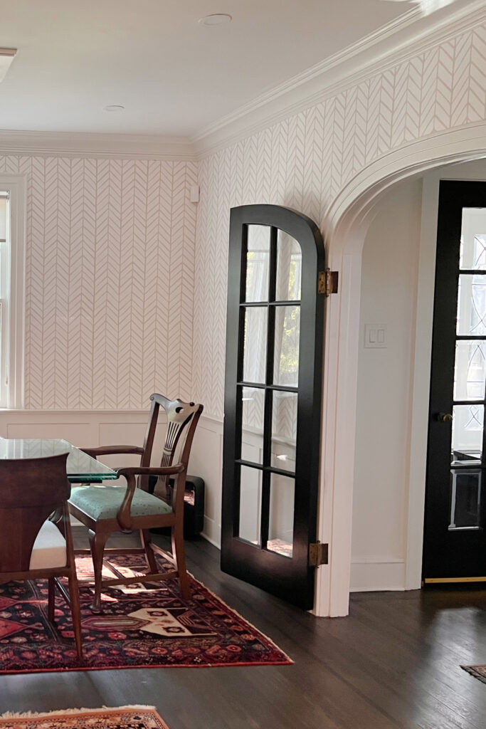 Black glass arched or rounded door, Serena and Lily Feather wallpaper, trim similar to Sherwin Williams Agreeable Gray, dark wood floor. Kylie M client photo