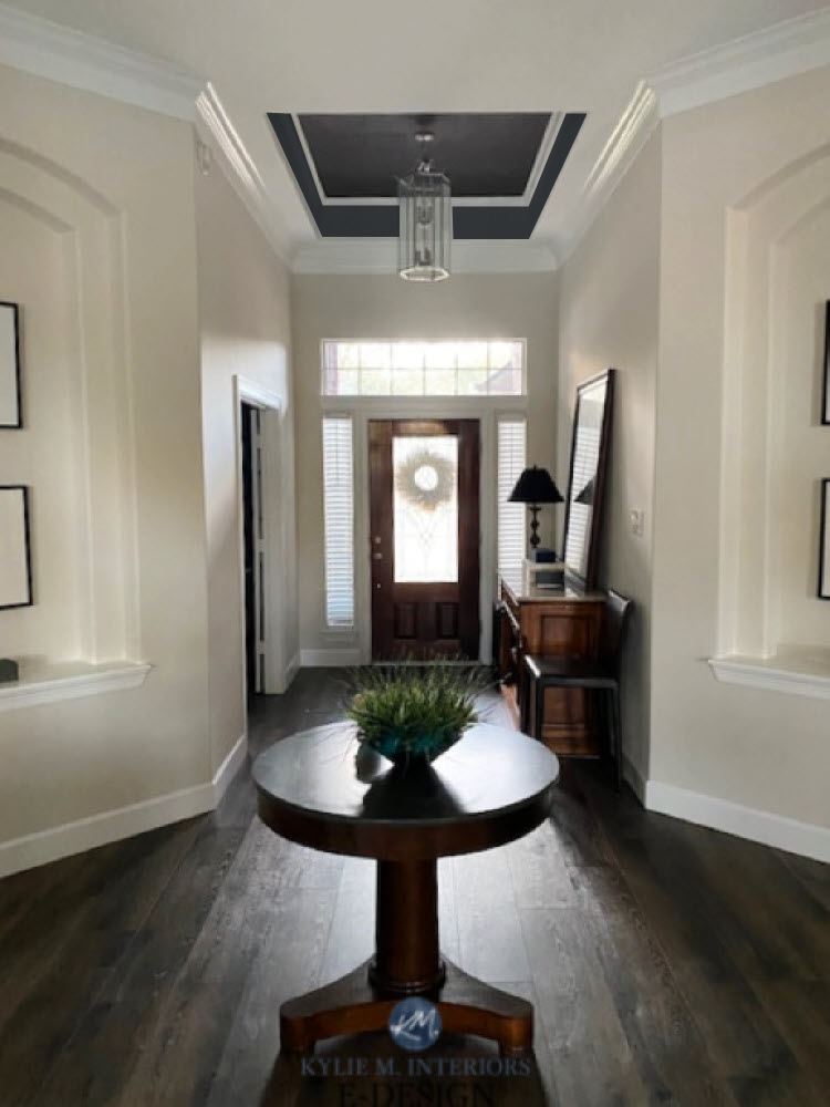 Entryway with tray ceiling painted a dark color, off-white Winds Breath walls, dark wood floor, Kylie M.