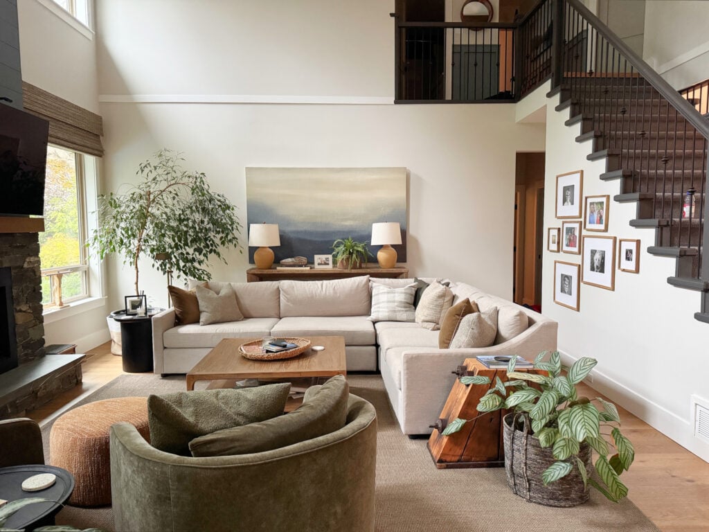 Sherwin Williams Aesthetic White in living room with north facing light, high, vaulted ceiling, Urbane Bronze painted stairs and sectional with oak floor