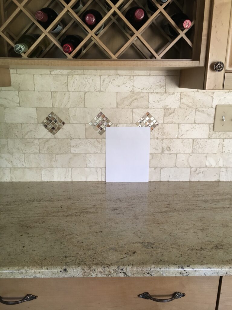 travertine tile backsplash with granite countertop and wood cabinets