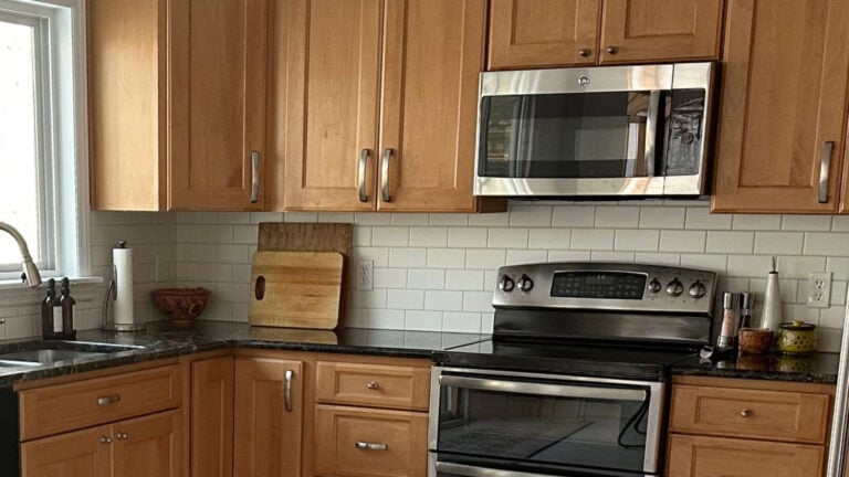 2000s kitchen update with maple wood cabinets, off-white subway tile backsplash, black granite countertop