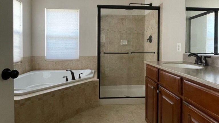 Ideas to update 2000s Tuscan beige bathroom with cherry red maple cabinets, beige tile and black shower surround and fixtures